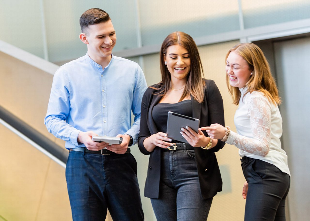 Justin looking at a Tablet with colleagues and smiling