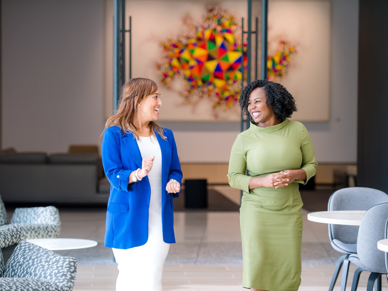 Two ladies in conversation in lobby, big abstract painting behind them