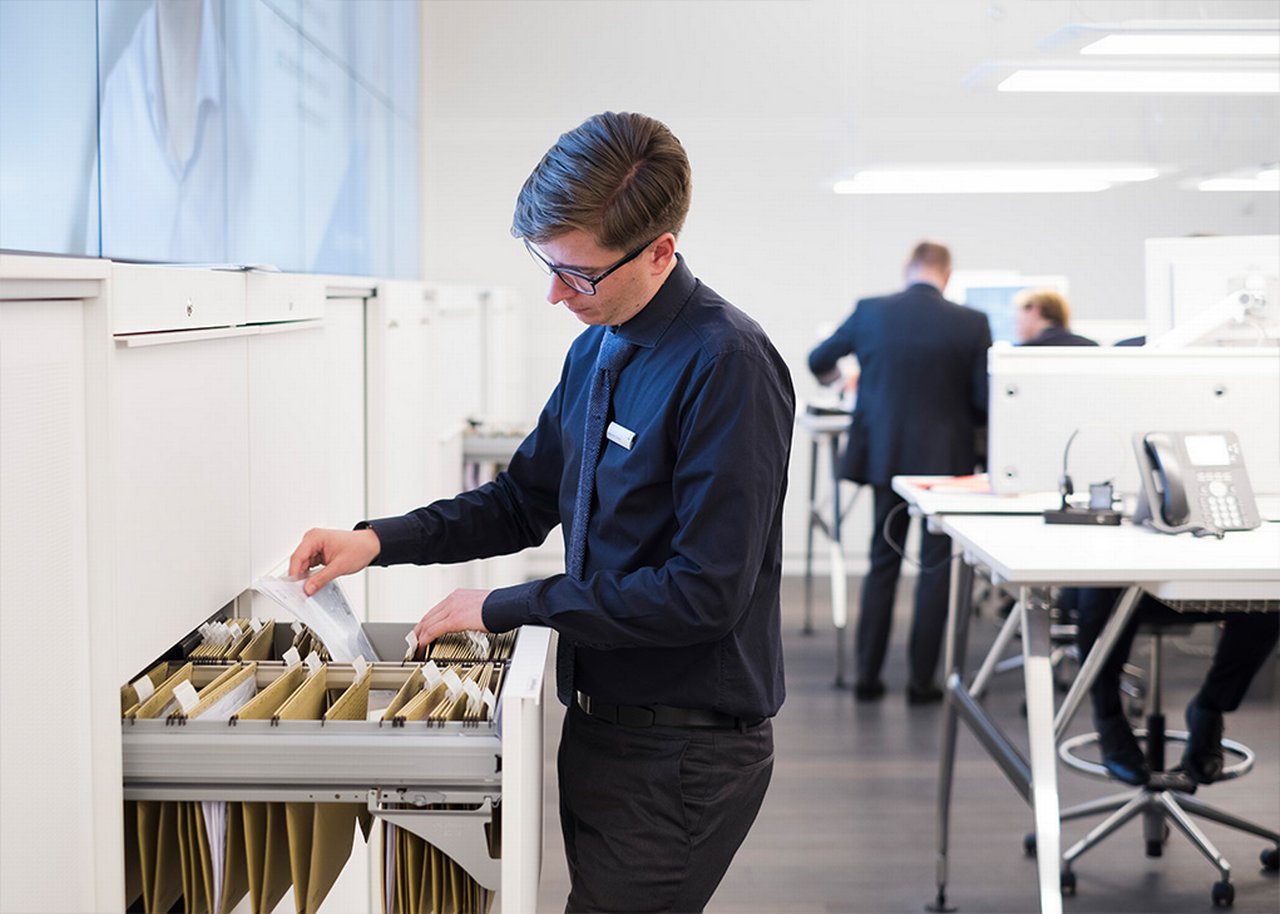 Alexander sortiert Akten in einem Aktenschrank