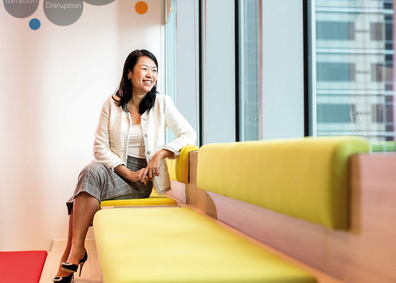 Wei Wei is sitting on a sofa smiling and looking out the window