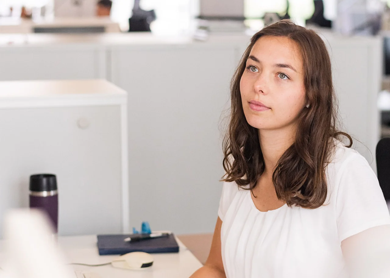 Giulia at her desk looking above and gazing attentively