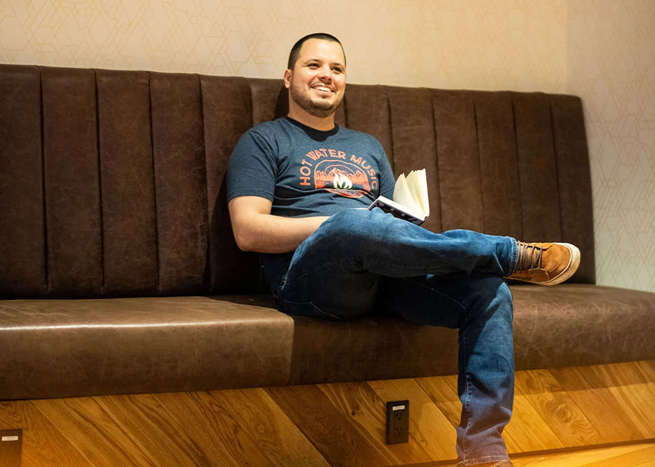 Ralf is sitting smiling with a book in his hand