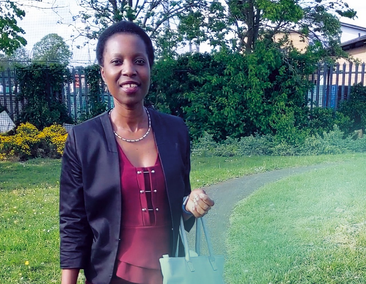 Melinda stands next to a grassy area in the park