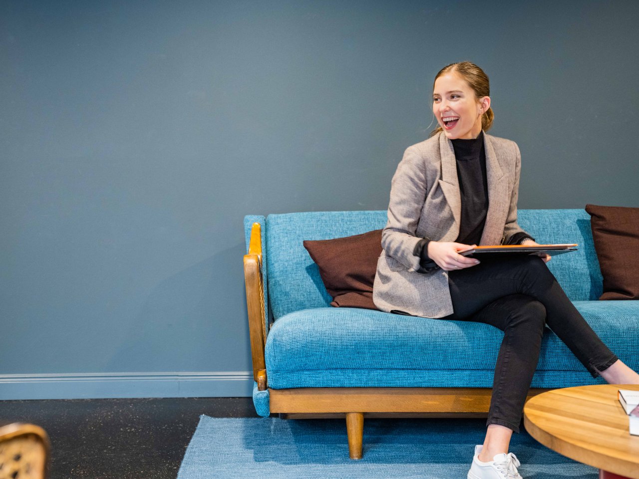 Happy young woman sitting on the couch holding documents on her lap