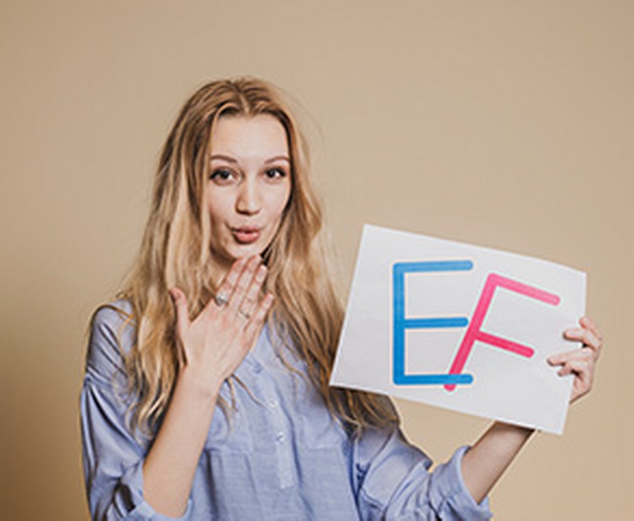 Ein Azubi bläst einen Kuss mit den Buchstaben E & F auf einem Schild in ihrer Hand