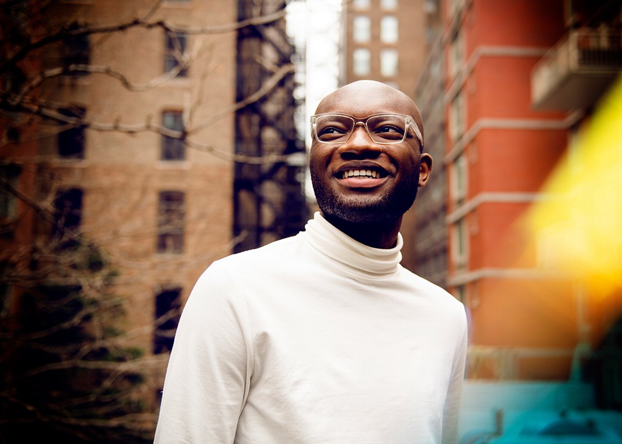 Kofi smiling between two tall buildings