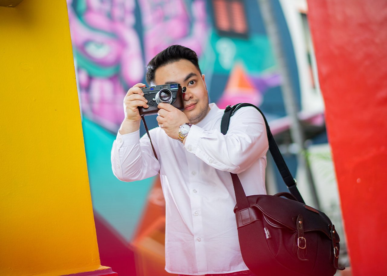 Bryan takes photographs in front of colorful wall