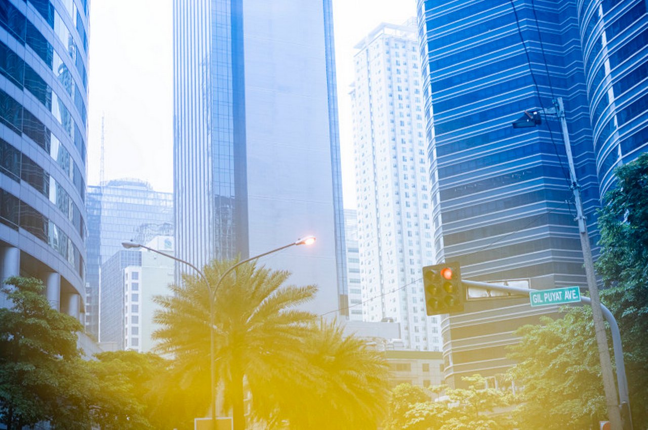 Skyscrapers, palm trees and a red traffic light in Manila