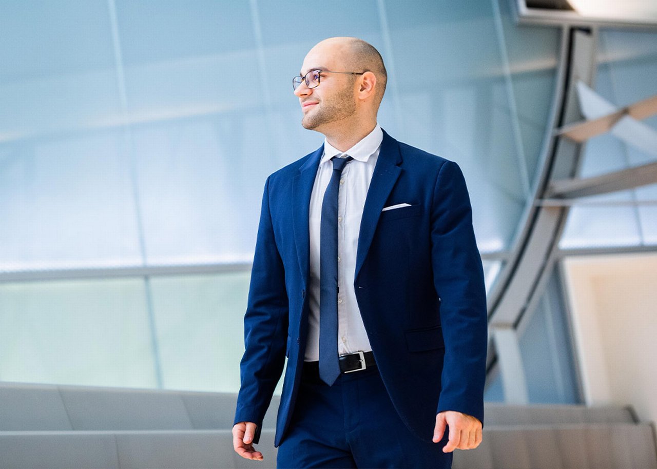 Erit is outside in front of a tall glass building
