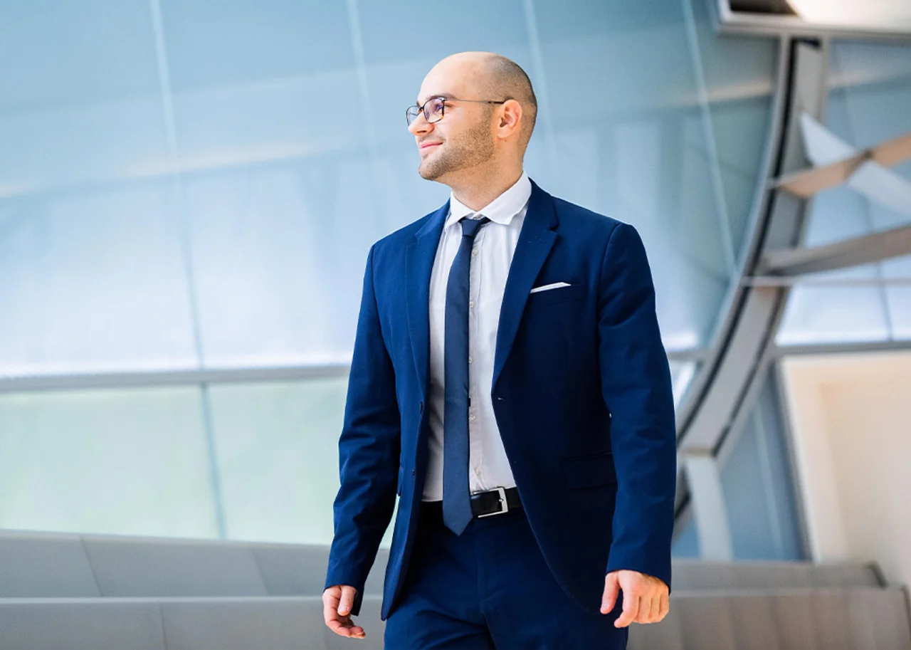 Erit is outside in front of a tall glass building