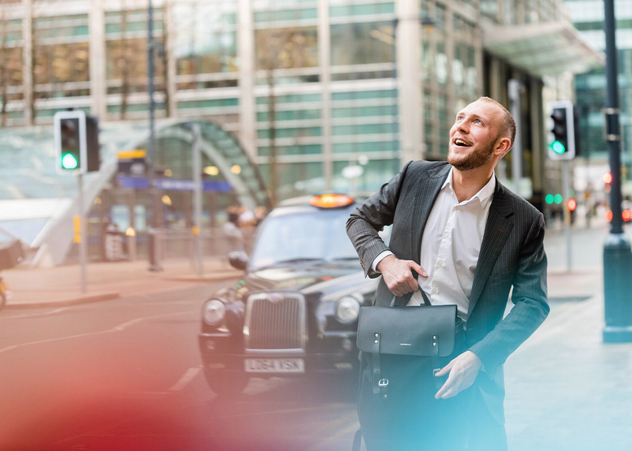 German is standing in front of a black cab with his briefcase in hand