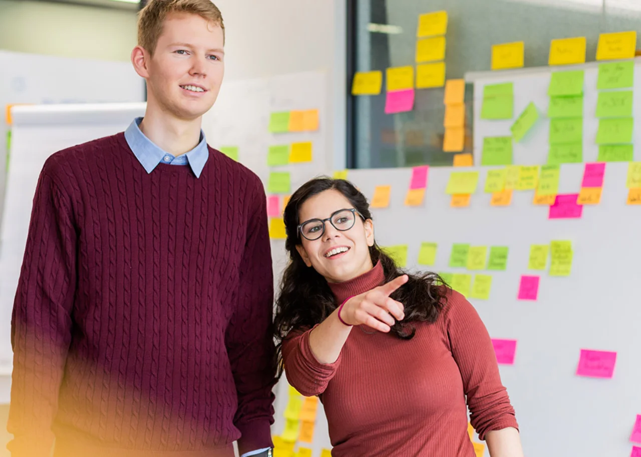 Sofie beside a colleague smiling and pointing her finger at something