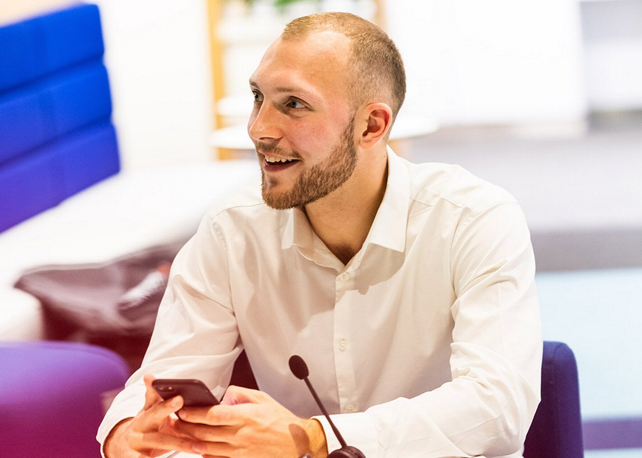 German is smiling in a conversation with his phone in his hand