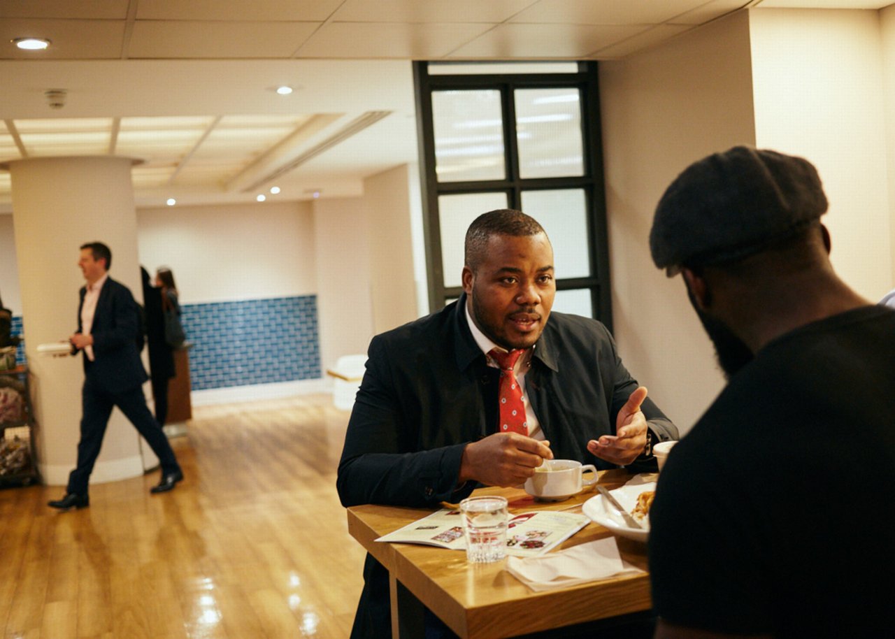Selasi and collegue sitting on a table and talking to each other
