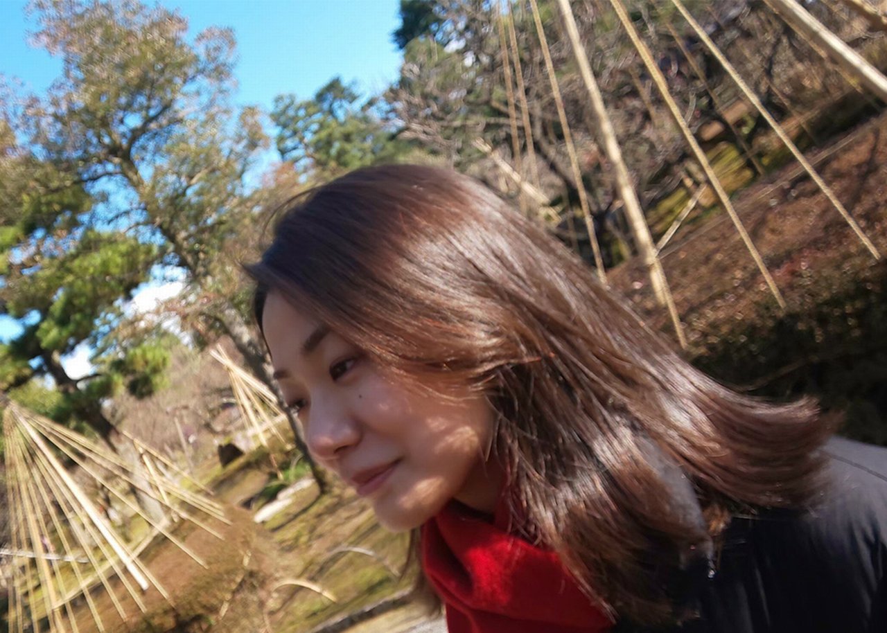 Kyoko outdoors in front of vegetable growing pyramids