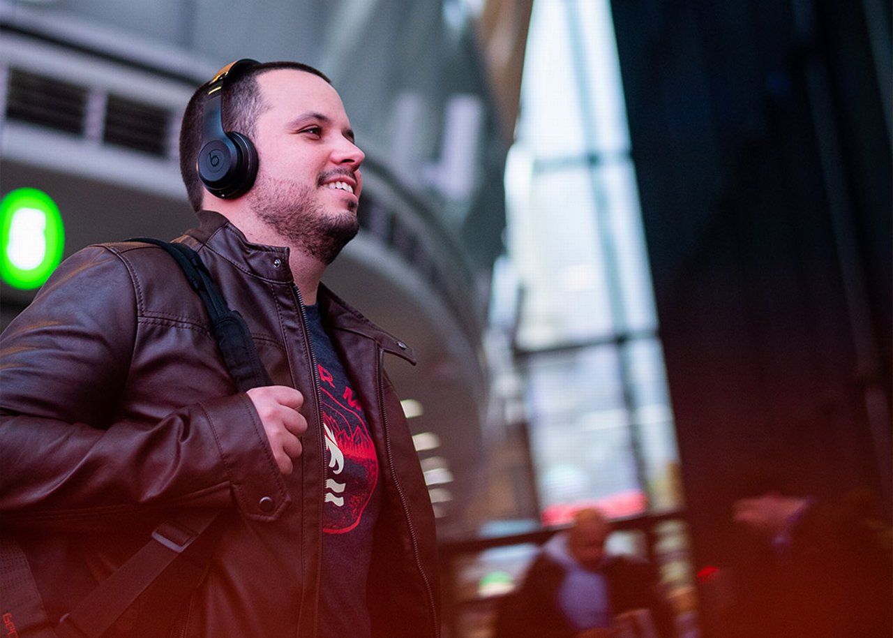 Ralf is walking through a foyer smiling with headphones on