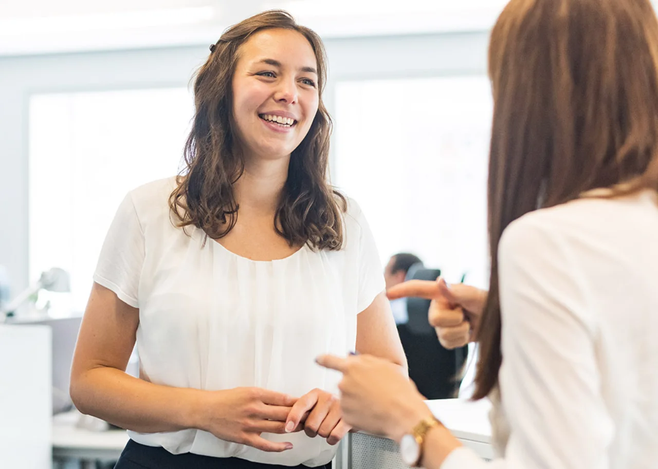 Giulia is smiling in conversation with a colleague