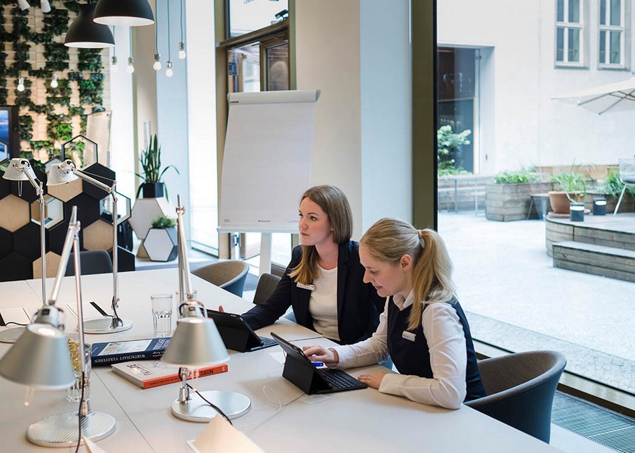 Marleen und eine Kollegin sitzen in einem modernen Büro mit Glasscheibe zum Innenhof