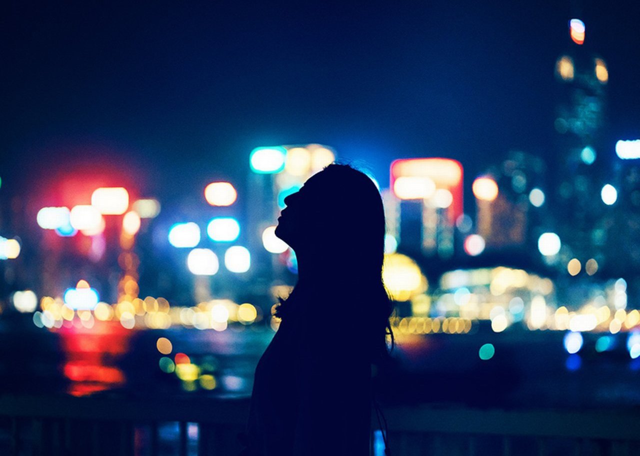 Eine Frauensilhouette vor den verschwommenen Lichtern einer Stadt