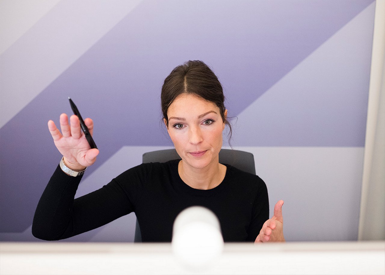 Juliane is sitting behind her desk making gestures during a video call