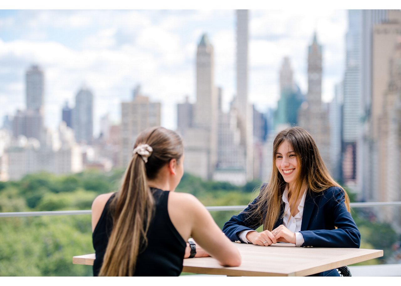 Isabel smiling while in conversation with a colleague on a terrace