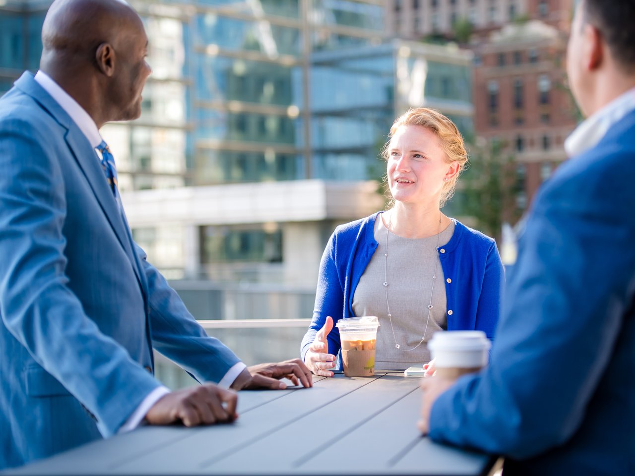 Collegues on a Coffee break at the Terrace with the city view behind them