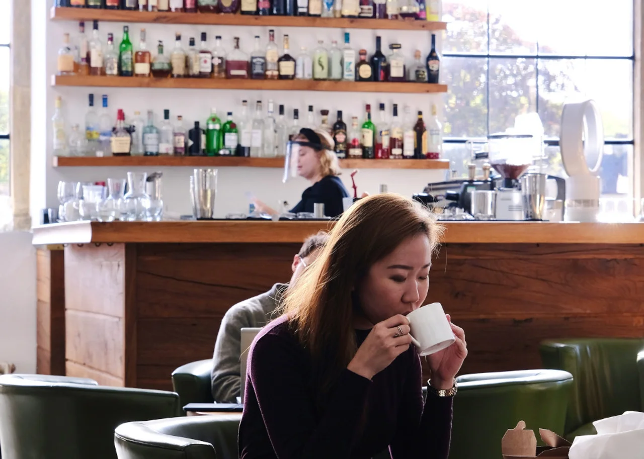 Queenie in a bar sipping a cup of tea