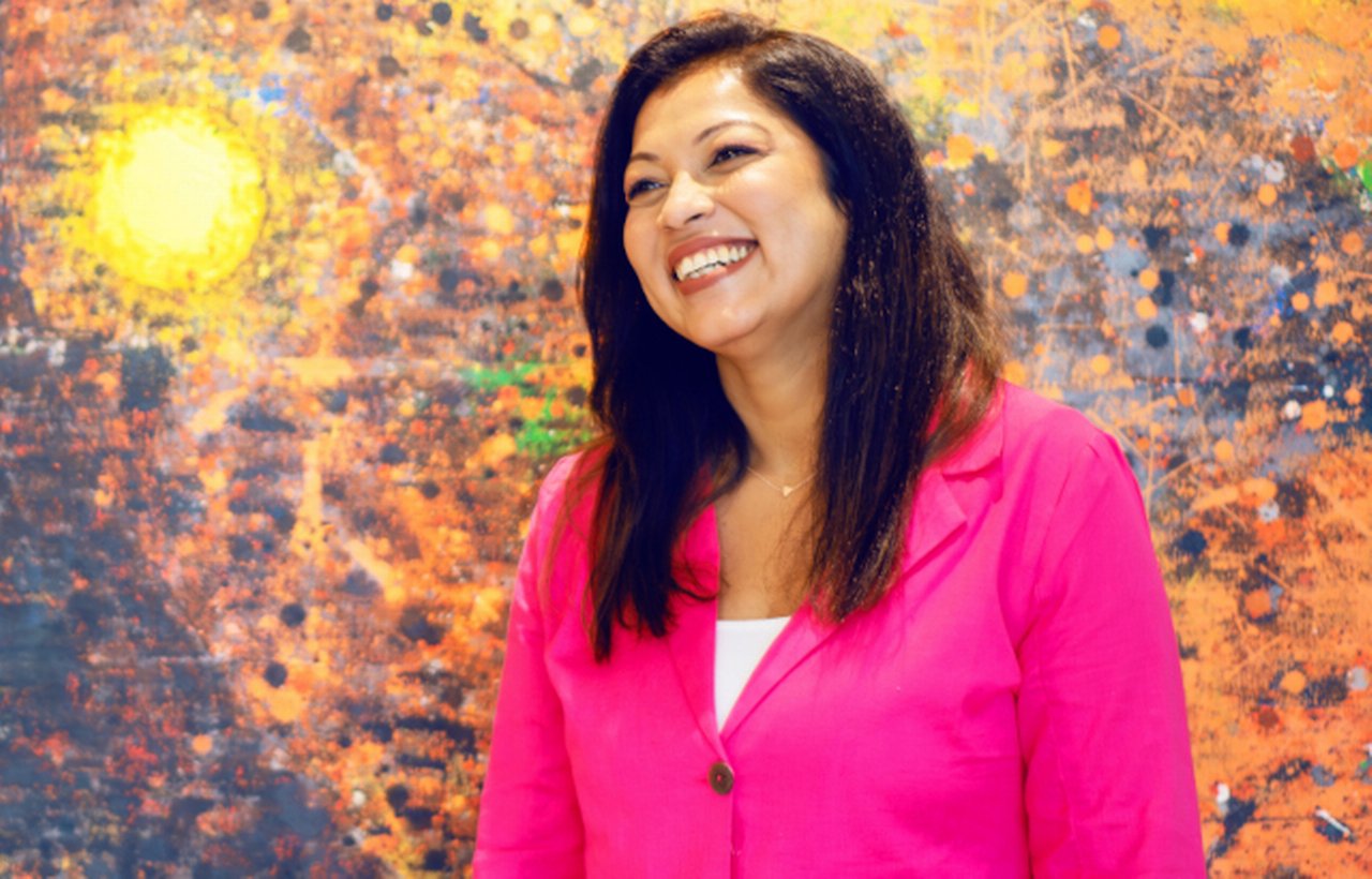 Woman standing infront of colorful wall smiling