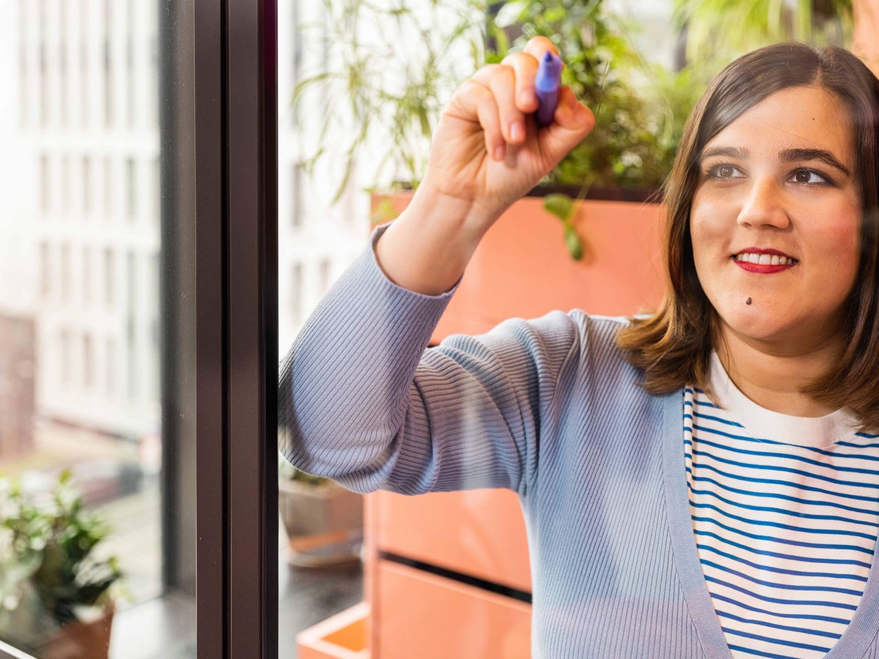 Eine Frau schreibt ihre Ideen auf eine Glasscheibe