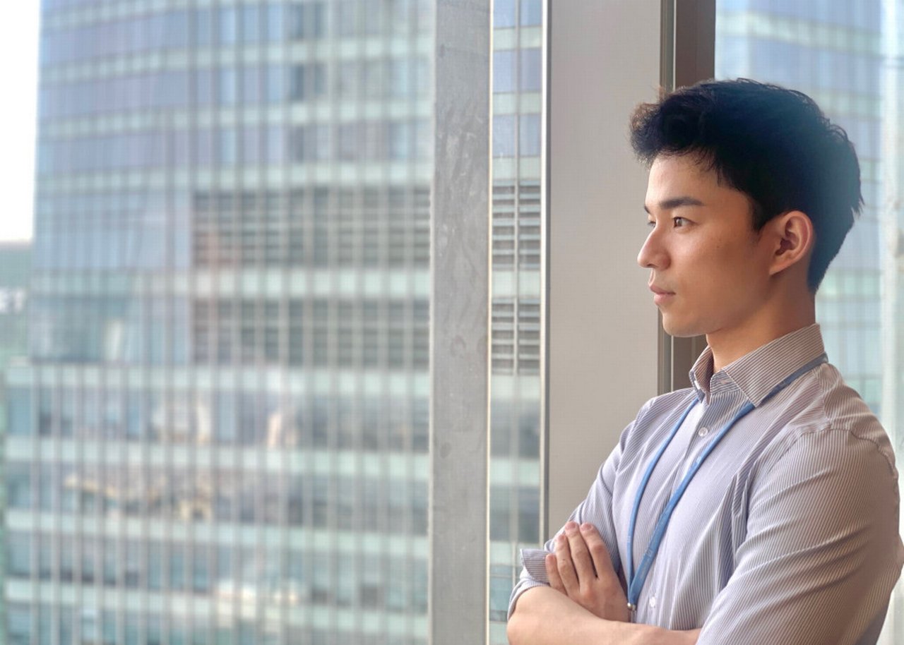 Sean stands in front of a window in a Deutsche Bank skyscraper
