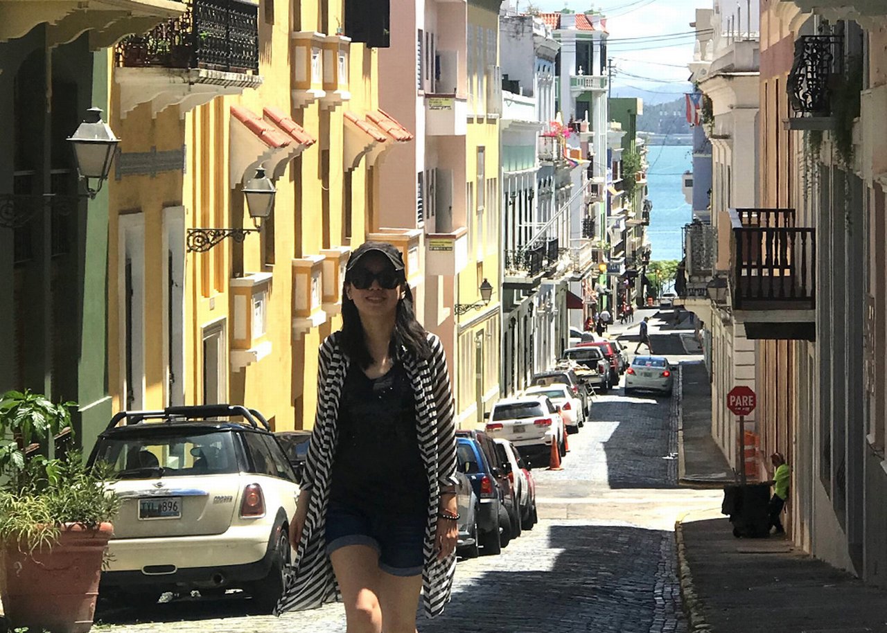 Woman on the narrow street buildings and parked cars on both sides