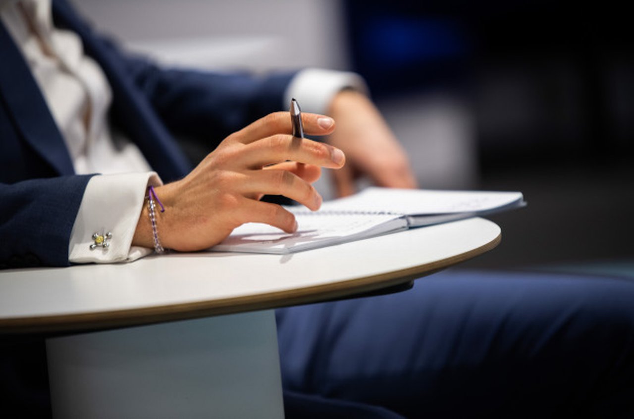 Person in the suit sitting at the table, pen in the hand
