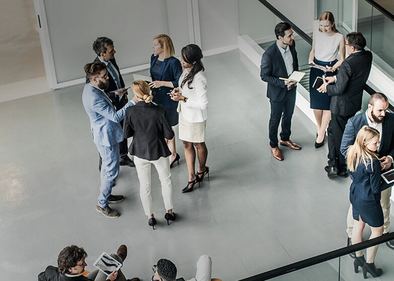Several people stand in small groups in a room
