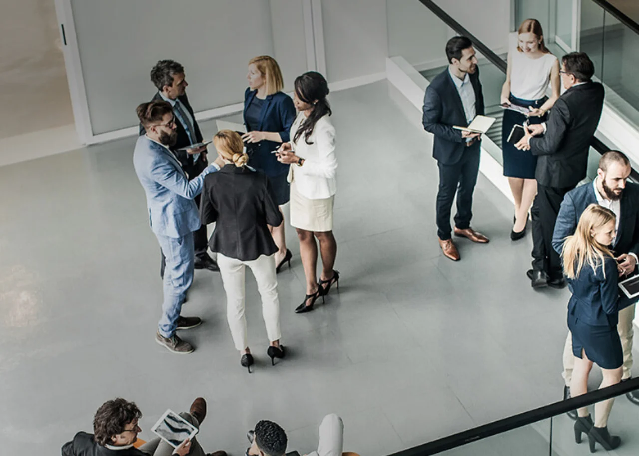 Several people stand in small groups in a room
