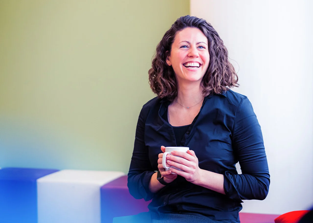 Erin lachend mit einem Kaffee