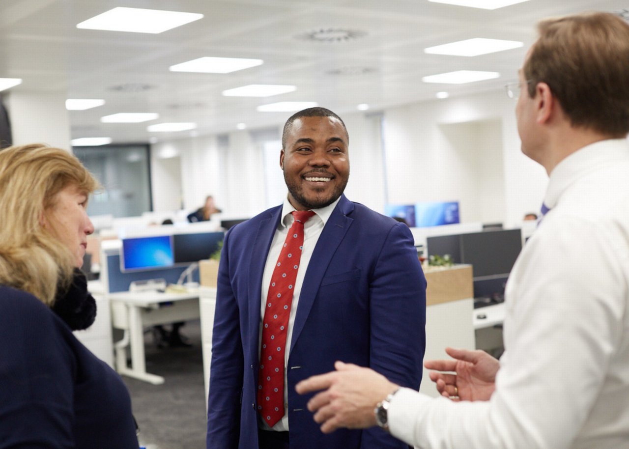 Selasi and two colleagues are talking in an open-plan office