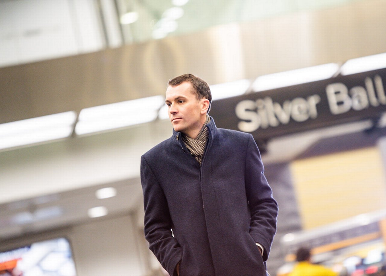 Mike steht in einem Foyer und posiert mit den Händen in der Tasche