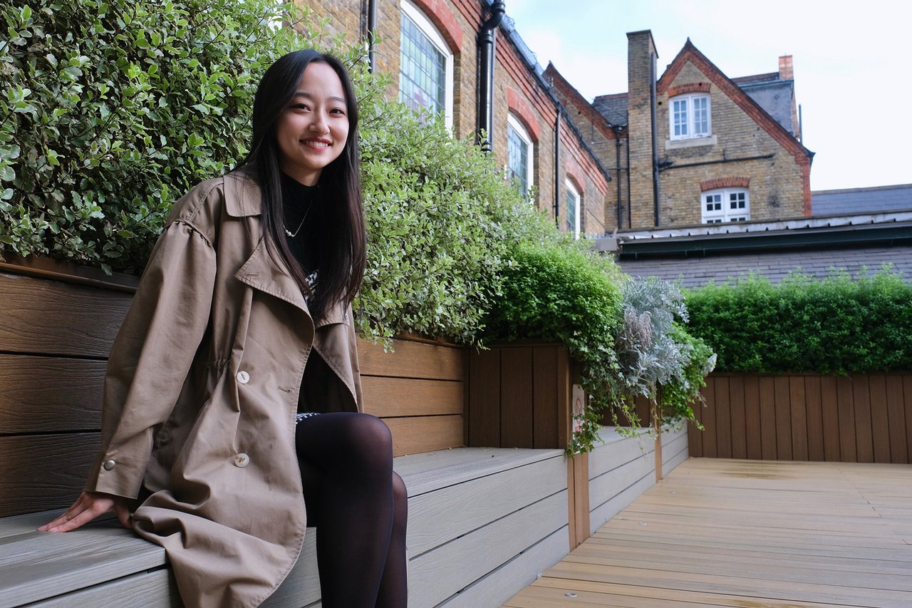 Mohan sits on a wooden bench and smiles