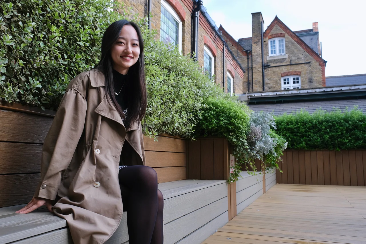 Mohan sits on a wooden bench and smiles
