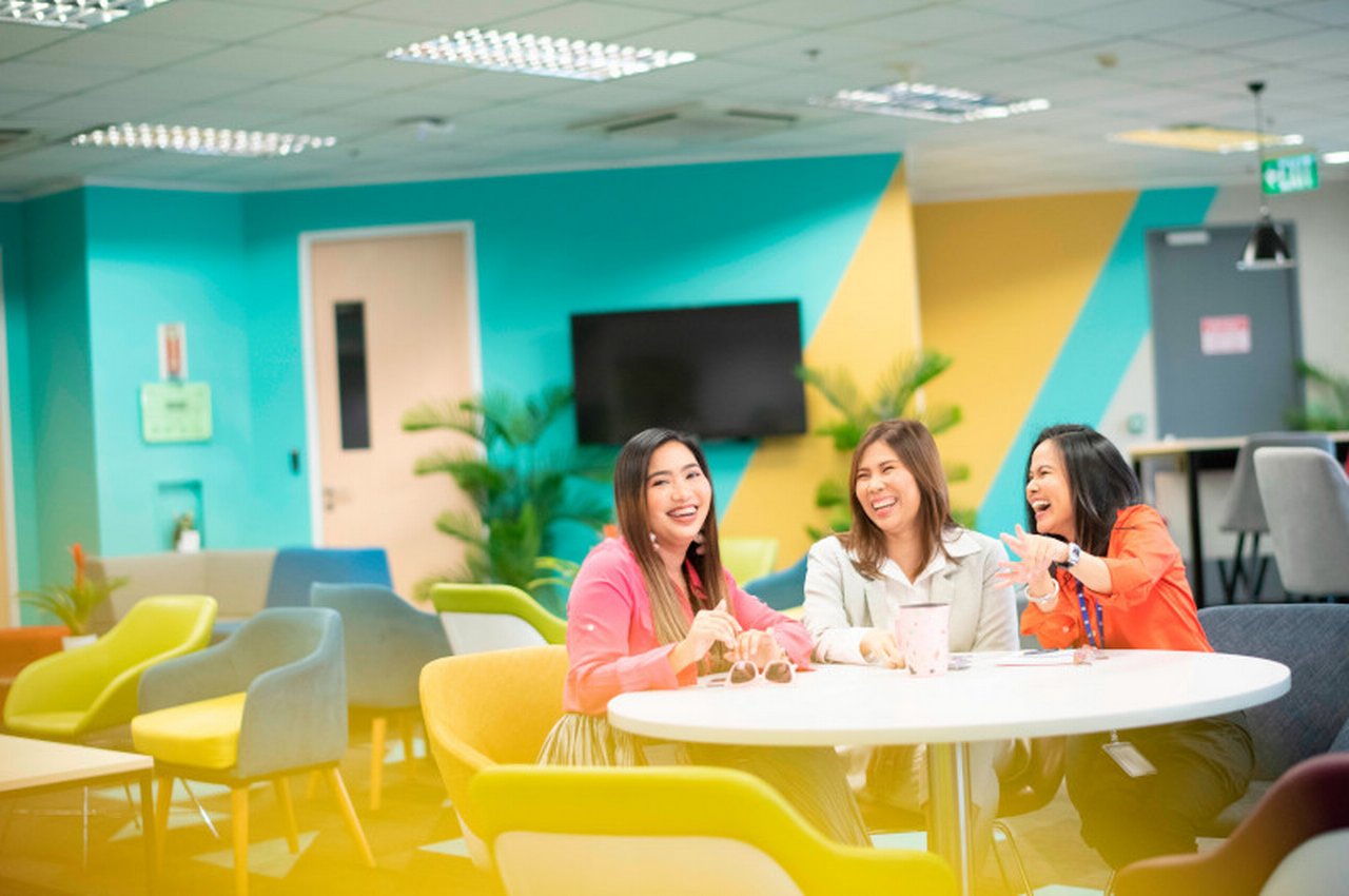 Three colleagues are sitting at a table, laughing