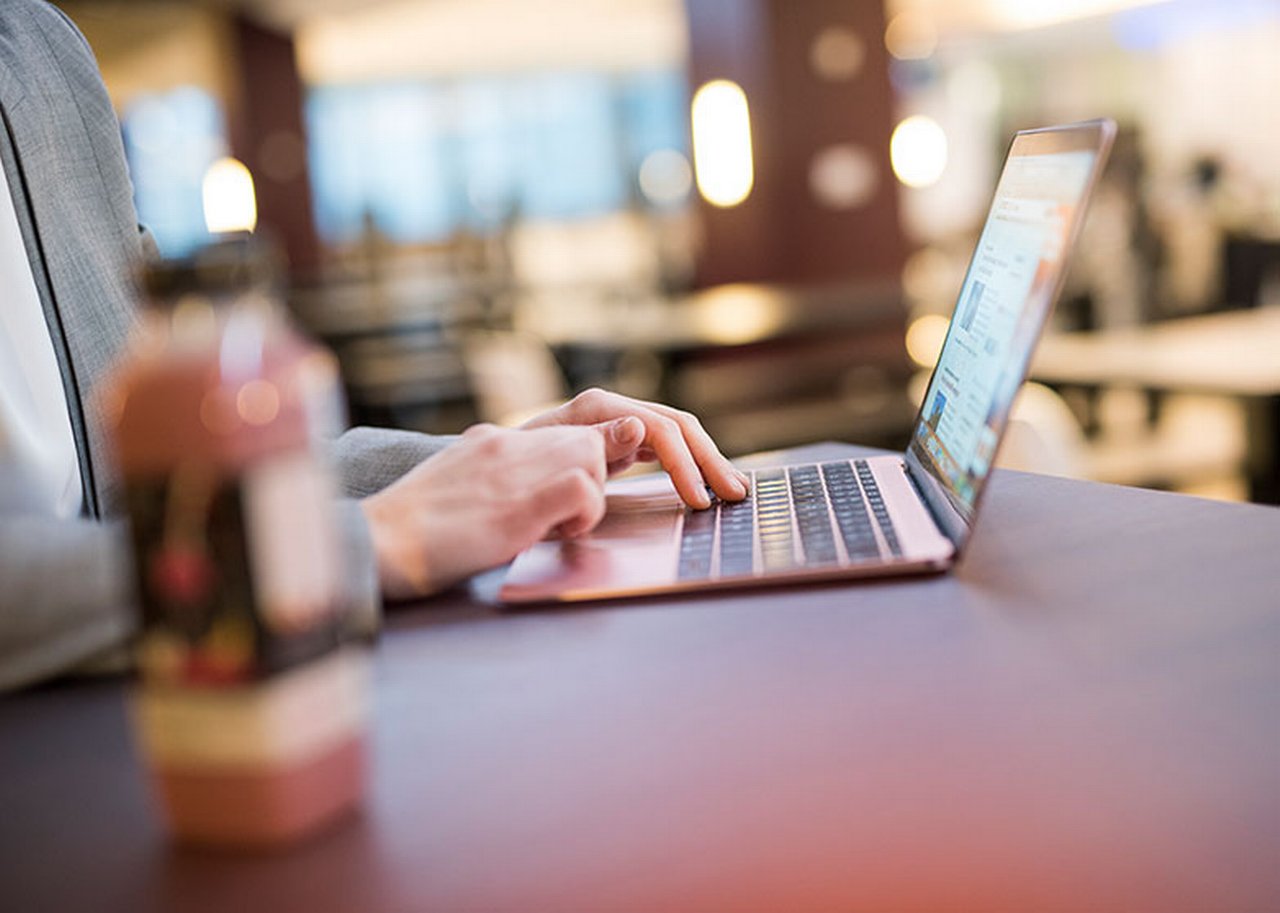 A close-up of a laptop on which a man in a suit is typing.