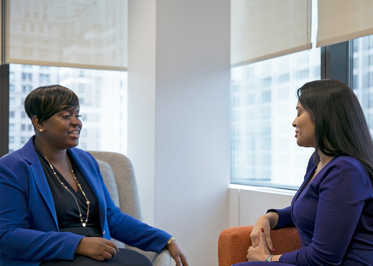 Kamalita sitting on a sofa having a conversation with Kisha
