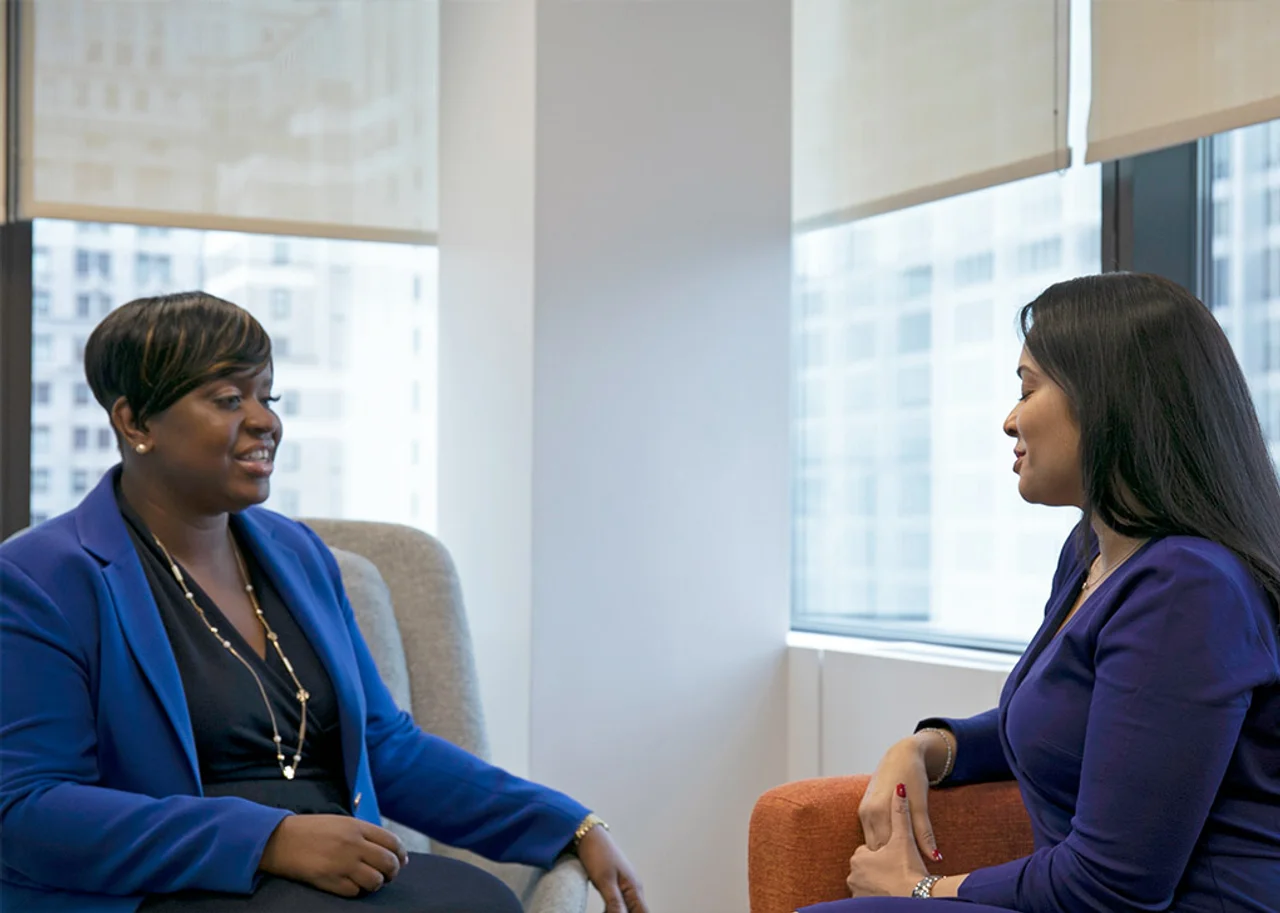 Kamalita sitting on a sofa having a conversation with Kisha