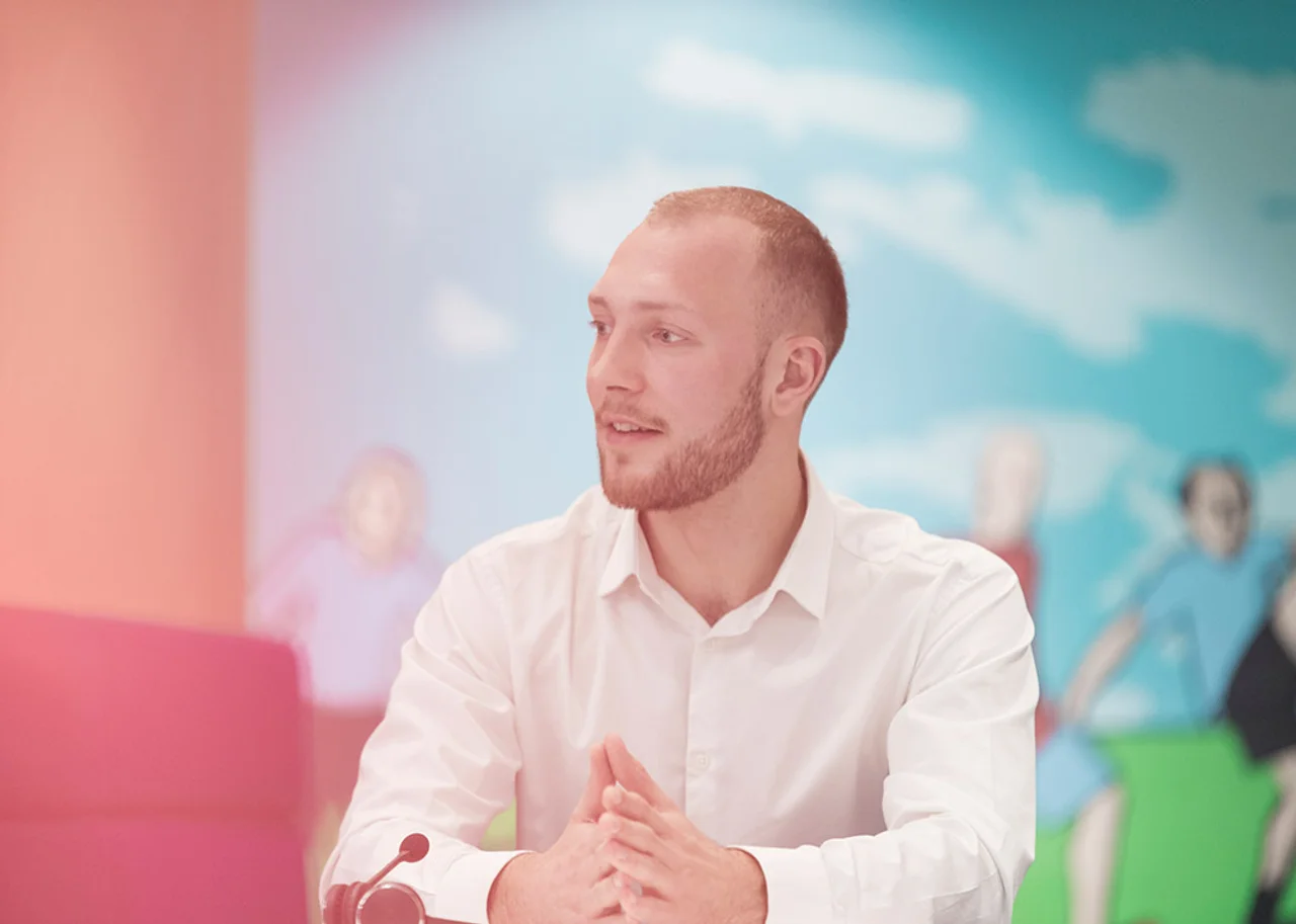 German sitzt vor einem bunten Hintergrund