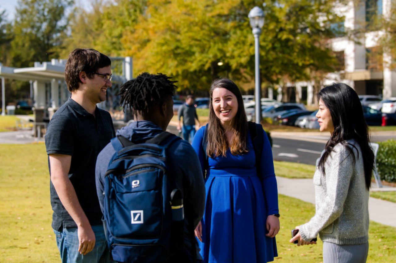 four people standing in circle talking outside