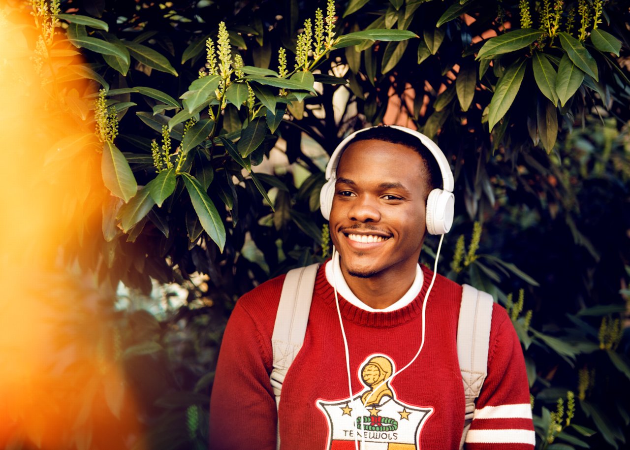 Jerry with headphones on standing in front of plants
