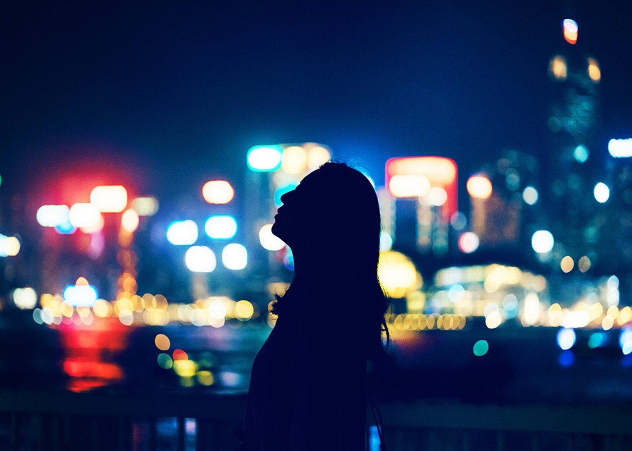 Eine Frauensilhouette vor den verschwommenen Lichtern einer Stadt