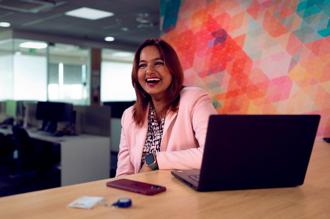 laughing employees in front of their laptops in the Deutsche Bank branch in Bangalore