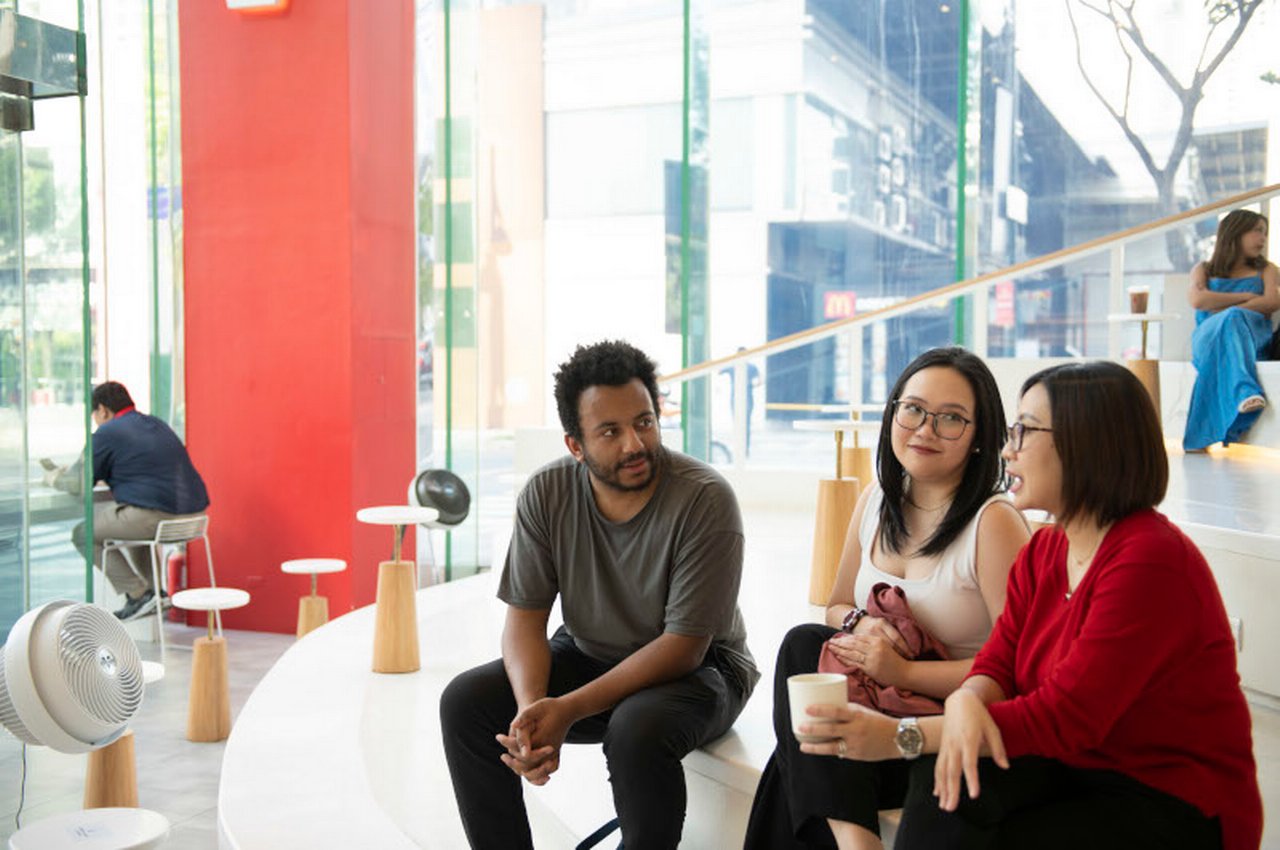 Several colleagues are sitting on a staircase in the foyer