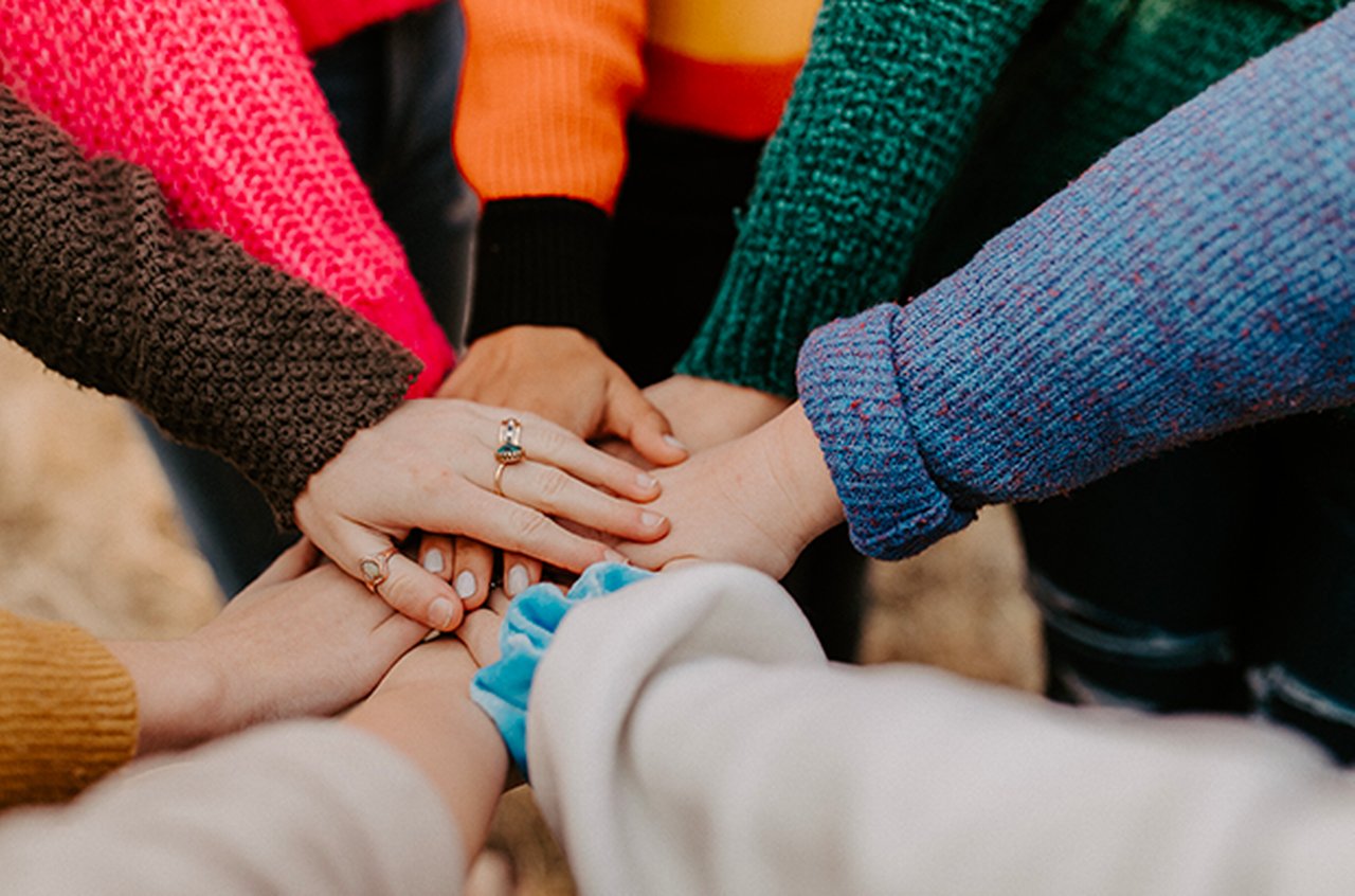 A group of people put their hands on top of each other in a circle